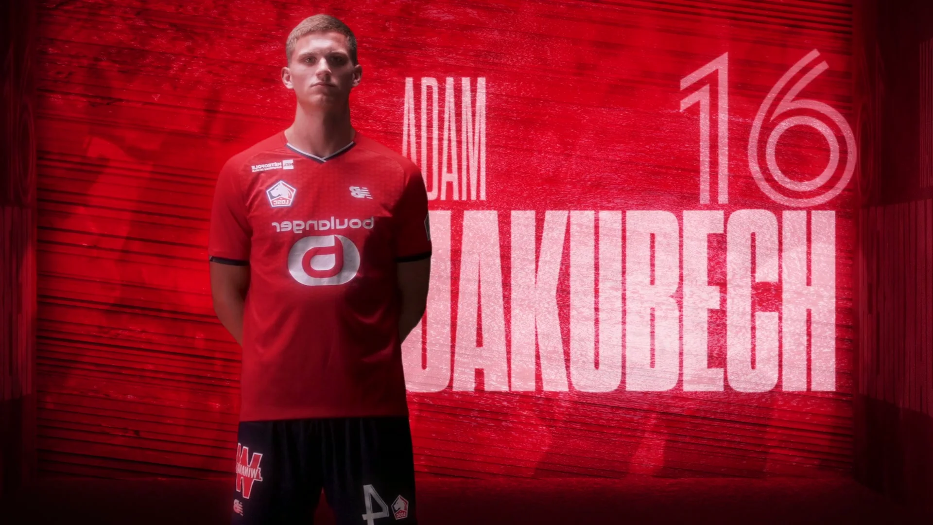 A player in front of ADAM JAKUBECH lettering and the number 16 in a textured red set.